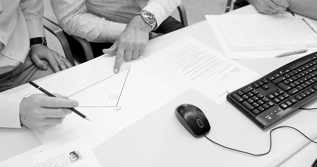 paper on a desk with man pointing at a triangle